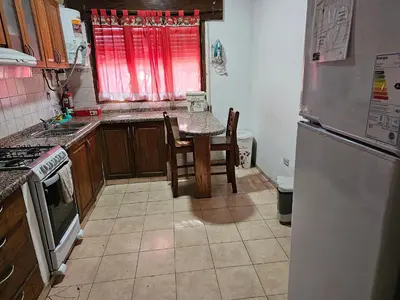 a kitchen with a table and a refrigerator at Mi casa, equipada para el viajero y su familia in Cordoba