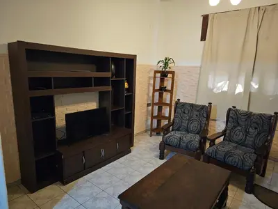 a living room with a flat screen tv and two chairs at Mi casa, equipada para el viajero y su familia in Cordoba