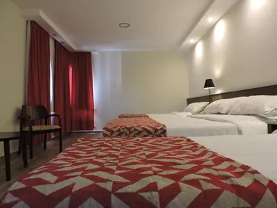 a hotel room with two beds and a red curtain at Los Espinillos Hotel y Spa in Villa Carlos Paz
