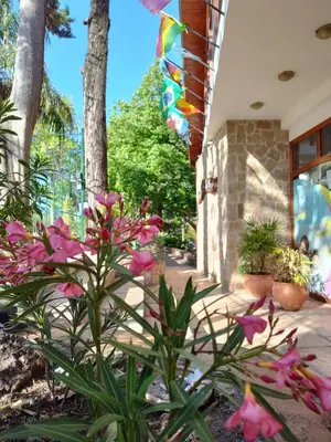 a garden with pink flowers in front of a building at Los Espinillos Hotel y Spa in Villa Carlos Paz