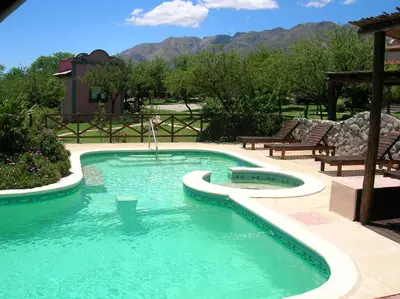 a swimming pool in a yard with chairs and mountains at Posada Los Antiguos-Adults Only in Merlo