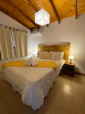 a bedroom with a large white bed in a room at Cabañas Los Maderos in Villa General Belgrano