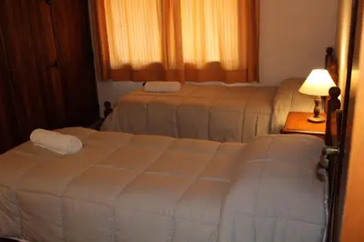 a bedroom with two beds and a table with a lamp at Cabañas Los Maderos in Villa General Belgrano