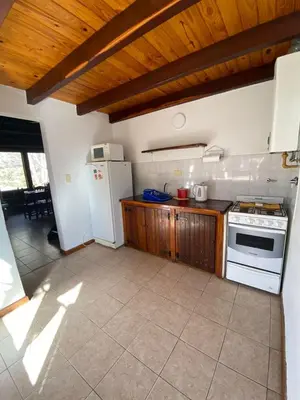 a kitchen with a white refrigerator and a stove at Cabañas Los Maderos in Villa General Belgrano