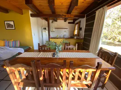 a dining room with a wooden table and chairs at Cabañas Los Maderos in Villa General Belgrano