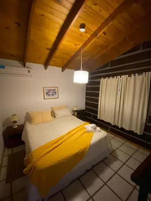 a bedroom with a bed with a yellow blanket on it at Cabañas Los Maderos in Villa General Belgrano