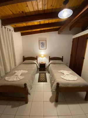 a bedroom with two beds and a table with a lamp at Cabañas Los Maderos in Villa General Belgrano
