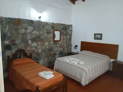 a bedroom with two beds and a stone wall at La Posta del Mistol in Las Tapias