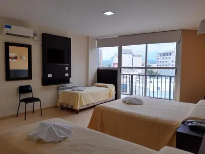 a hotel room with two beds and a balcony at Hotel Presidente in Villa Carlos Paz