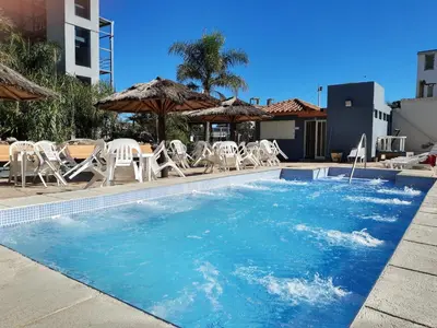 a swimming pool with chairs and umbrellas at Hotel Presidente in Villa Carlos Paz