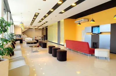 a lobby with a red couch and chairs and tables at Hotel Presidente in Villa Carlos Paz