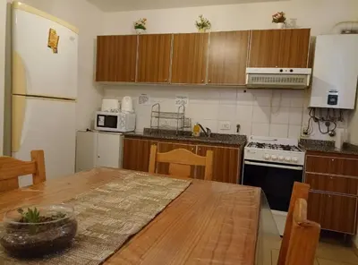 a kitchen with wooden cabinets and a table and a refrigerator at Apartamentos Santa Rosa PB 2 in Cordoba