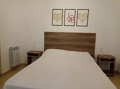 a bedroom with a white bed with three pictures on the wall at Apartamentos Santa Rosa PB 2 in Cordoba
