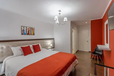 a bedroom with a large bed with an orange blanket at Posada del Tiempo in Merlo
