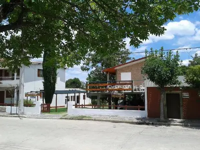 a building on the side of a street with a tree at HOSTERIA NIDO DE CONDORES-Solo Adultos in Mina Clavero