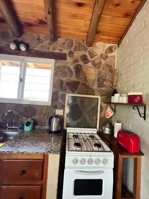 a kitchen with a stove and a stone wall at Al Encuentro Casas de Montaña in Nono