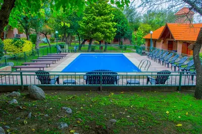 a swimming pool with chairs around it in a park at Complejo Vip Houses in Merlo