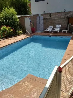 a large swimming pool with two chairs and a fence at Hotel Gala in Villa Carlos Paz