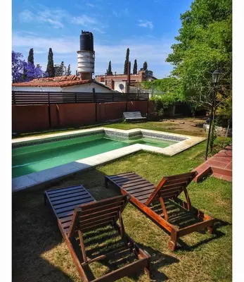 two chairs and a swimming pool in a yard at La Caballeriza habitación doble in Alta Gracia