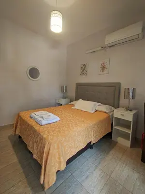 a bedroom with a bed with a orange blanket at La Caballeriza habitación doble in Alta Gracia