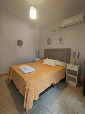 a bedroom with a bed with a orange bedspread at La Caballeriza habitación doble in Alta Gracia