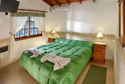 a green bed in a room with a green blanket at Cabañas Los Duendes in Villa General Belgrano
