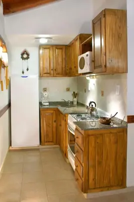 a kitchen with wooden cabinets and a white refrigerator at Cabañas Los Duendes in Villa General Belgrano