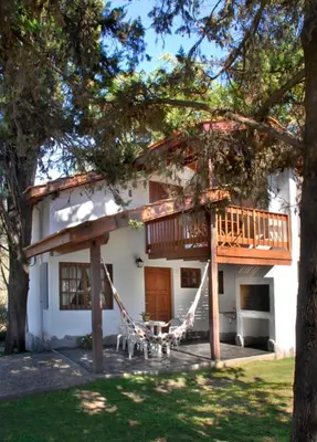 a house with a deck and a porch with a table at Cabañas Los Duendes in Villa General Belgrano