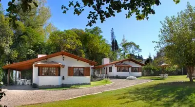 a white house with a yard with a driveway at Cabañas Los Duendes in Villa General Belgrano