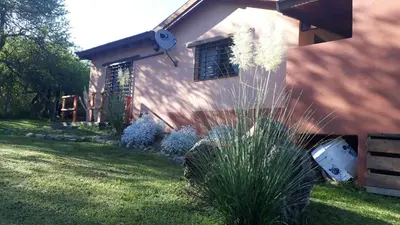 a house with a grass yard next to a house at Cabañas Rosaditas in Santa Rosa de Calamuchita
