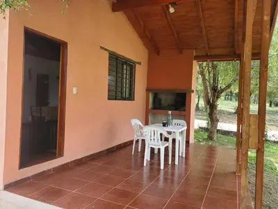 a porch of a house with a table and chairs at Cabañas Rosaditas in Santa Rosa de Calamuchita
