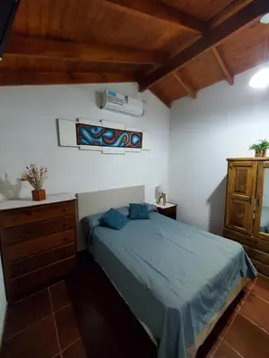 a bedroom with a bed and a dresser in a room at Cabañas Rosaditas in Santa Rosa de Calamuchita
