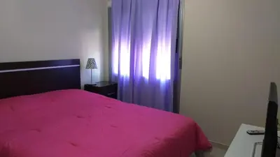 a bedroom with a pink bed and a purple curtain at alto villa sol in Cordoba