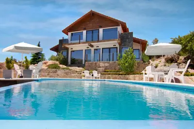 a house with a swimming pool in front of a house at Suites de la Colina in La Cumbrecita