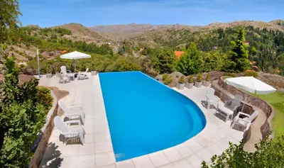 an overhead view of a swimming pool with chairs and umbrellas at Suites de la Colina in La Cumbrecita