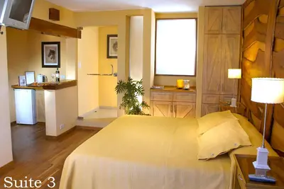 a bedroom with a large bed and a kitchen at Suites de la Colina in La Cumbrecita