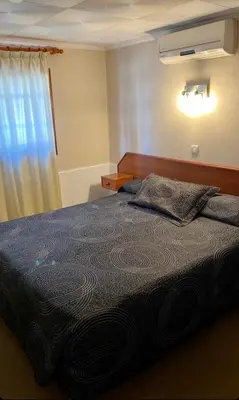 a bedroom with a bed with a blue blanket and a window at Hotel Samay Huasi in Villa General Belgrano