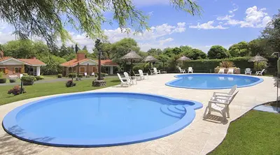 a large pool with chairs in a yard at Cabañas y Lofts El Portal in Villa General Belgrano