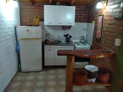 a kitchen with a white refrigerator and a table at Cabaña Tío Miguel in Los Molles