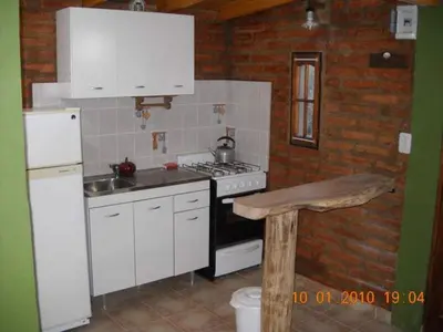 a kitchen with white cabinets and a stove and refrigerator at Cabaña Tío Miguel in Los Molles