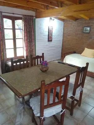 a dining room with a table and chairs and a bed at Cabaña Tío Miguel in Los Molles