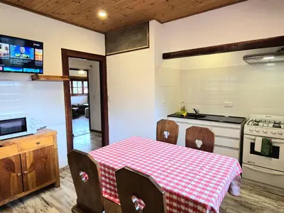 a kitchen with a table with chairs and a stove at Hotel La Cumbrecita in La Cumbrecita