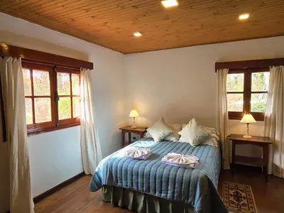 a bedroom with a bed with blue sheets and two windows at Hotel La Cumbrecita in La Cumbrecita