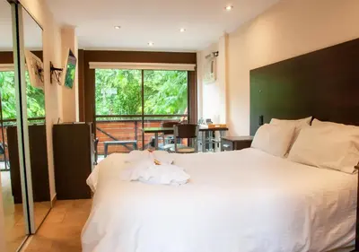 a bedroom with a large white bed and a balcony at Windmuhle Apart Hotel & Spa in Villa General Belgrano