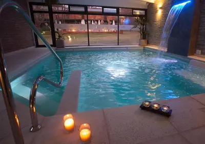 a swimming pool with candles and a bottle of beer in it at Windmuhle Apart Hotel & Spa in Villa General Belgrano