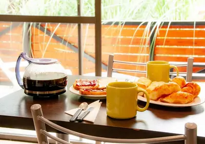 a table with two cups of coffee and a plate of pastries at Windmuhle Apart Hotel & Spa in Villa General Belgrano
