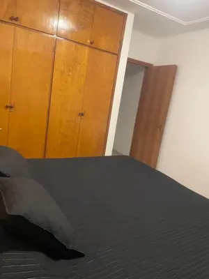 a bedroom with a black bed and a wooden cabinet at Alonso 540 Departamento in Río Cuarto