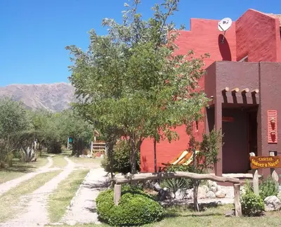 a red building with a tree next to a dirt road at Casitas Volver a Nacer in Carpintería