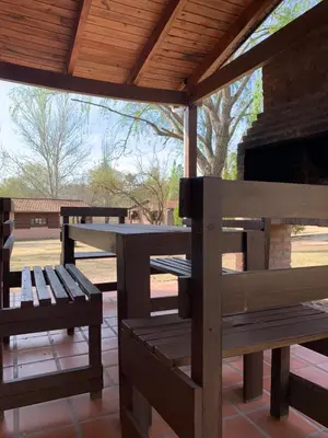 a picnic table and benches under a pavilion at El Camino Viejo Cabañas in Villa General Belgrano