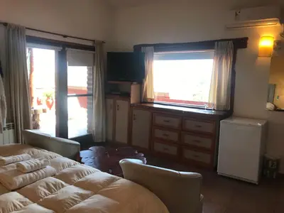 a bedroom with two beds and a dresser and two windows at Chalet Suisse Posada & SPA - Adults only in Villa General Belgrano